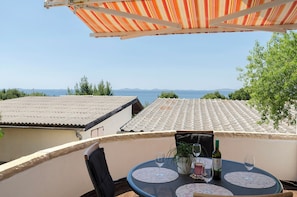 A terrace with a table, chairs, and a view of the sea. - Apartments Ema (Murter-Kornati)