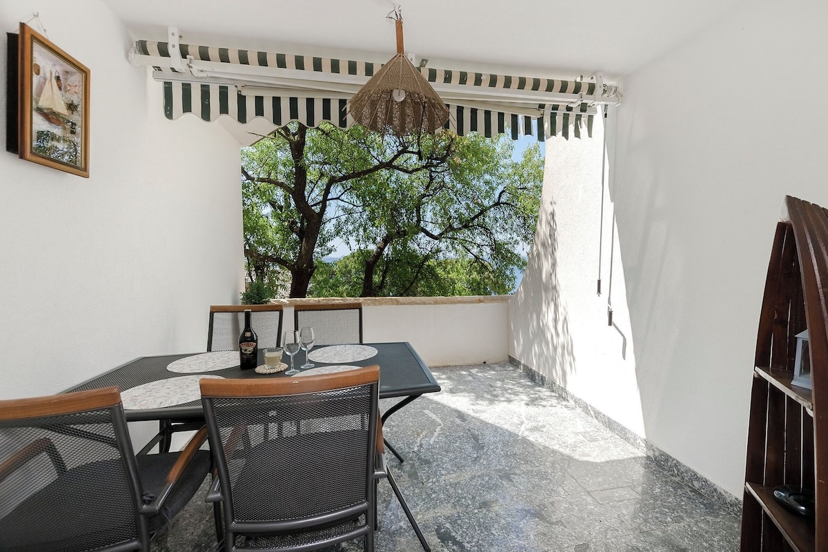 A dining area with a table, chairs, and a hanging light fixture.