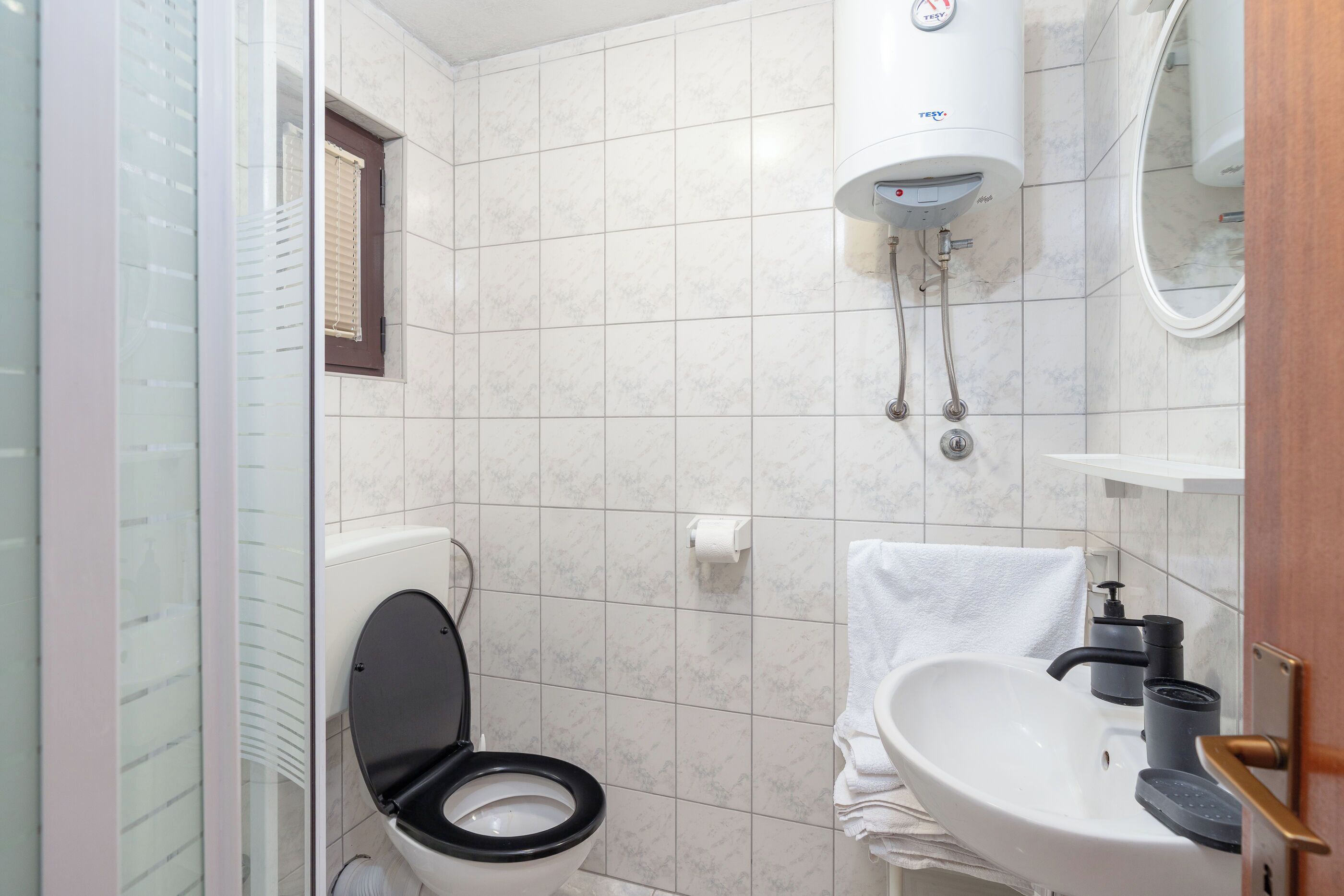 Un baño con inodoro, lavamanos, toallero y ducha.