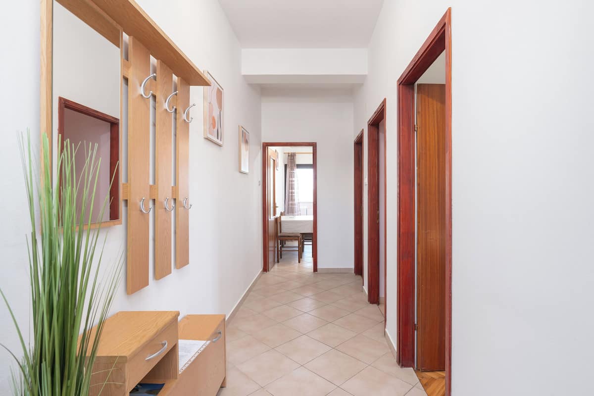 Un pasillo con puertas de madera, un banco de madera y una planta.