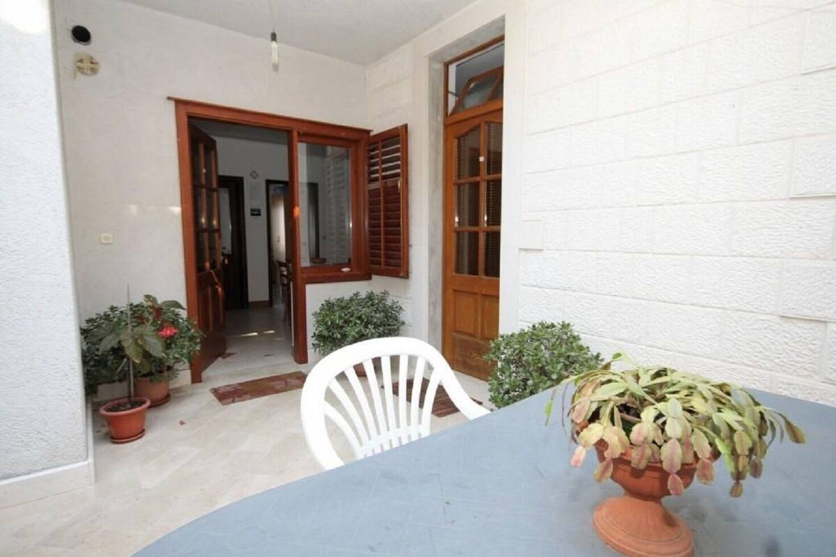 A small patio area with a table and chairs, potted plants, and a wooden door.