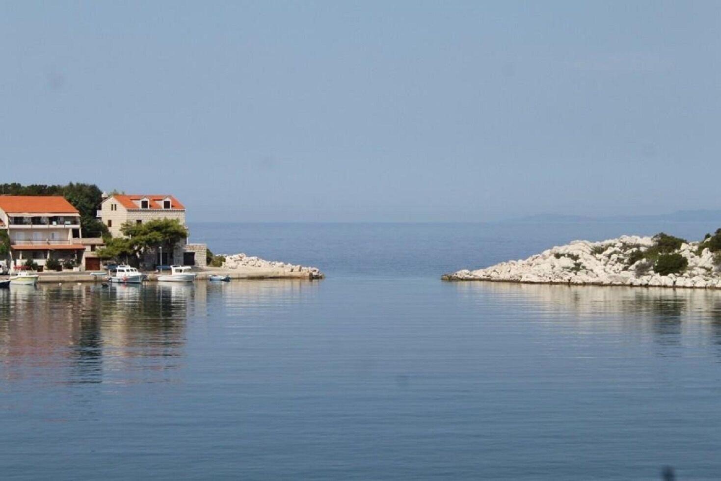 A coastal scene with buildings, boats, and rocky outcrops.