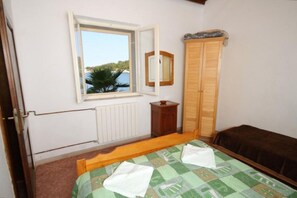 A bedroom with a bed, a window, a radiator, a wardrobe, and a mirror. - Apartment Milan (Lastovo)