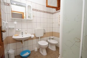 Ein Badezimmer mit Waschbecken, zwei Toiletten, einem Spiegel und einer blauen Waschschüssel.