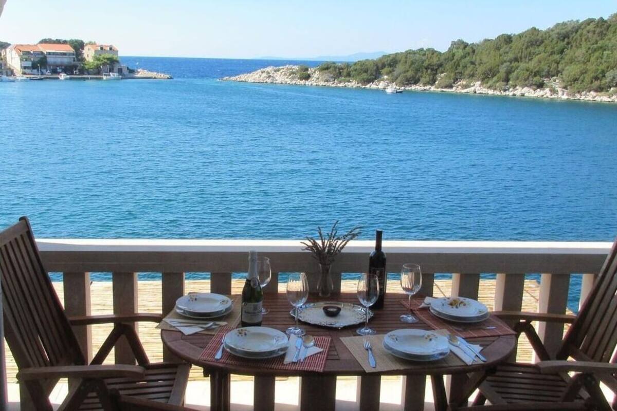 A table set for two with a view of the sea and a distant shoreline.