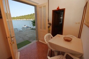 Ein Zimmer mit Meerblick, ein Tisch mit einem Korb und eine Tür, die nach draußen führt.