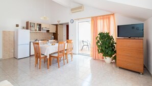 A compact living space with a kitchen, dining area, and a TV. - Apartment Orange (Postira)