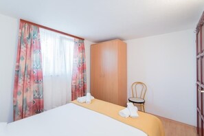 Quarto de hotel com uma cama, guarda-roupa, cadeira e mesa com toalhas.
