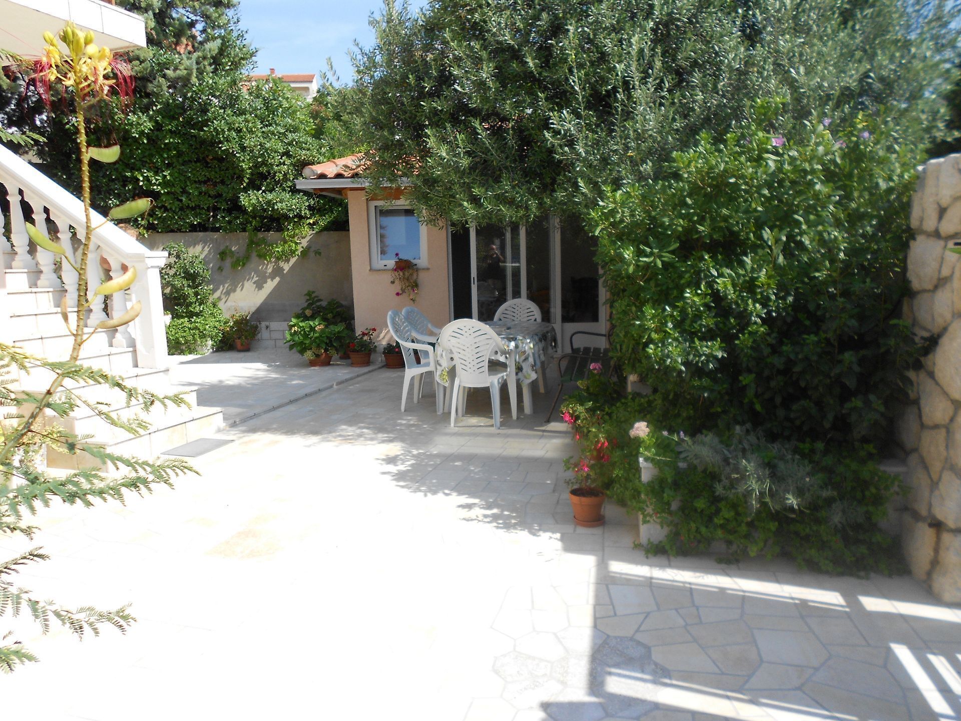 A patio area with outdoor seating, potted plants, and a stone wall.