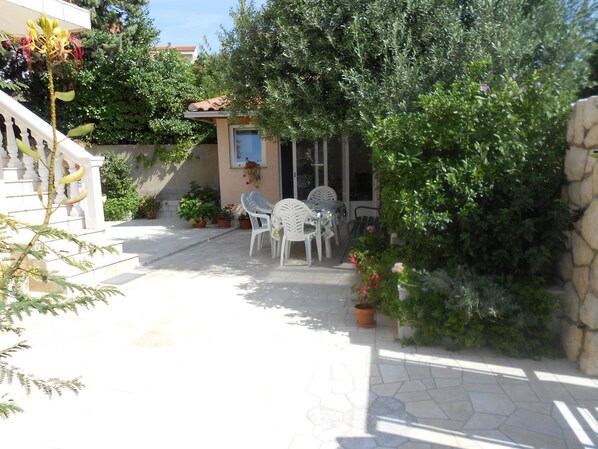 A patio area with outdoor seating, potted plants, and a stone wall. - Apartments Kate (Novi Vinodolski)