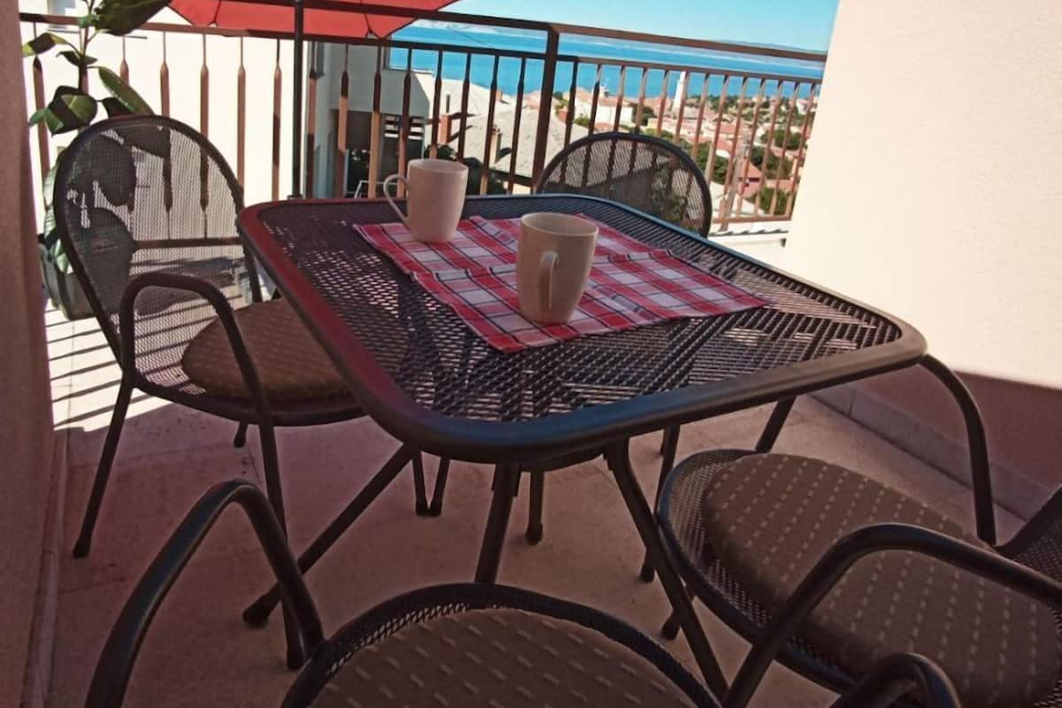 Un balcone con tavolo, sedie e un ombrellone rosso.