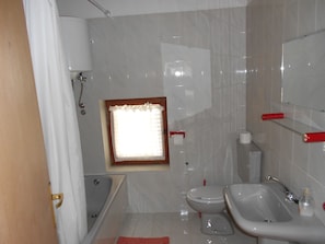 Casa de banho com banheira, sanita, bidé e lavatório.