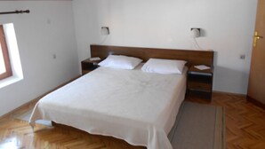 Camera da letto con soffitto in legno, un letto con biancheria bianca, due comodini e una finestra.