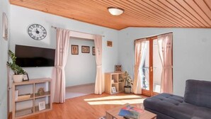 Un soggiorno con televisore, divano, tavolino e soffitto in legno.