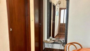 A hallway with a wooden door, a round table with chairs, a small round table with a decorative item, and a large mirror reflecting the room. - Apartments Matkov (Jelsa)
