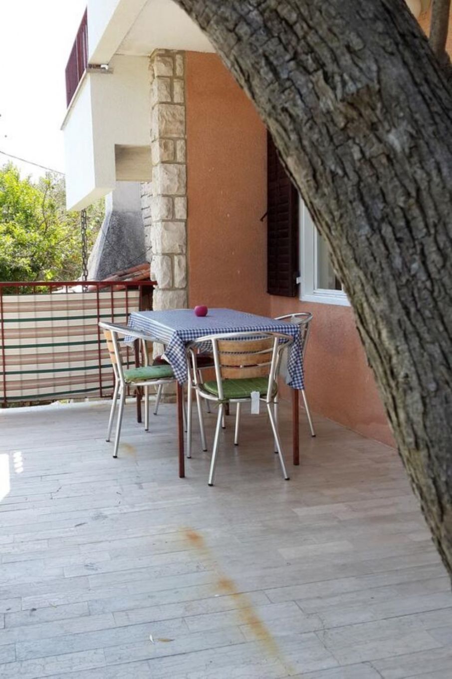 A patio with a table and chairs, a stone pillar, and a tree trunk framing the view.