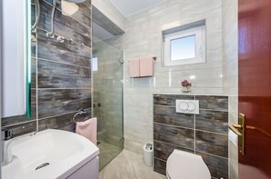A modern bathroom with a shower, toilet, and sink. - Apartments Dreamy (Nin)