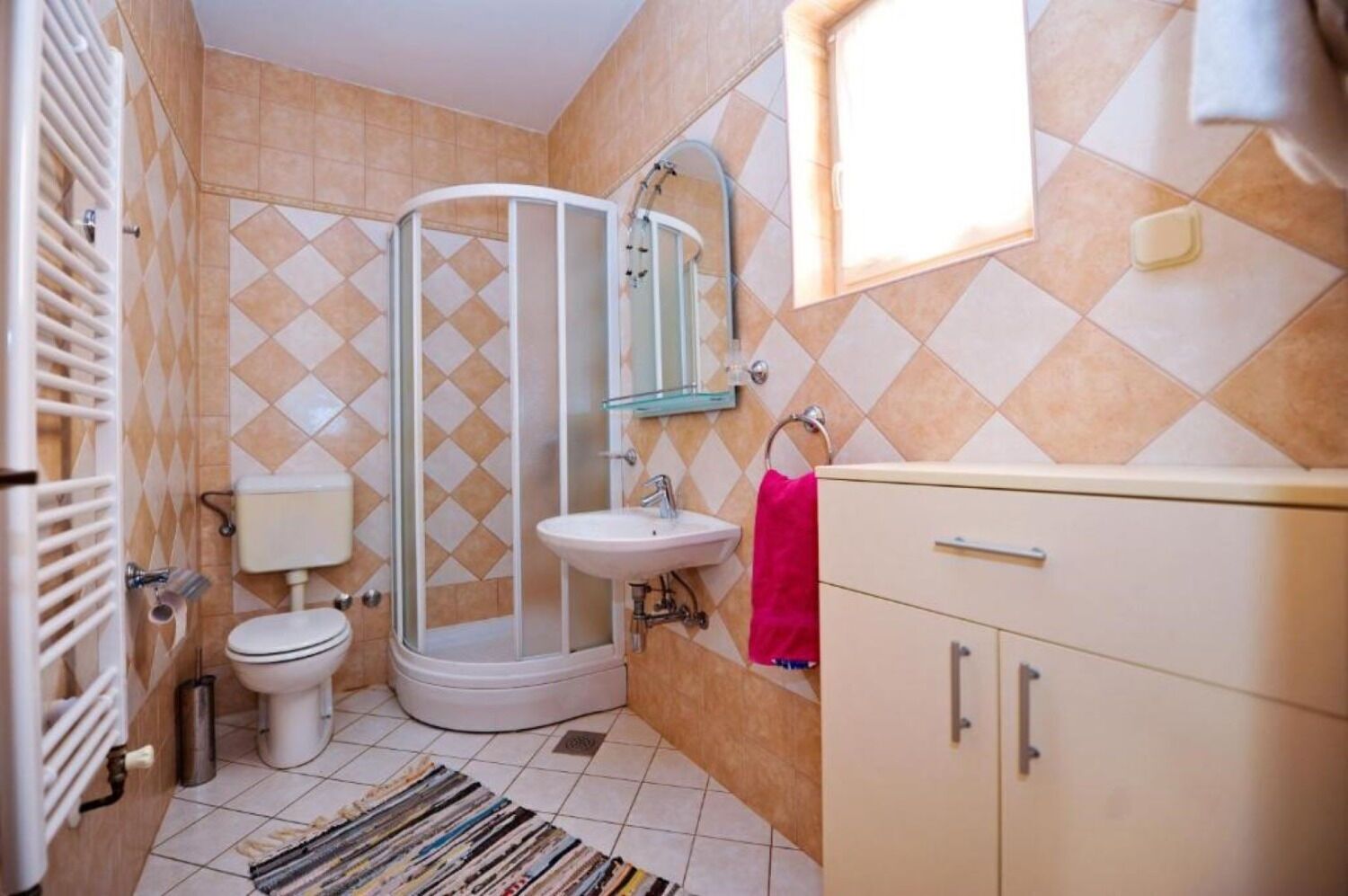A bathroom with a shower, toilet, sink, and vanity.