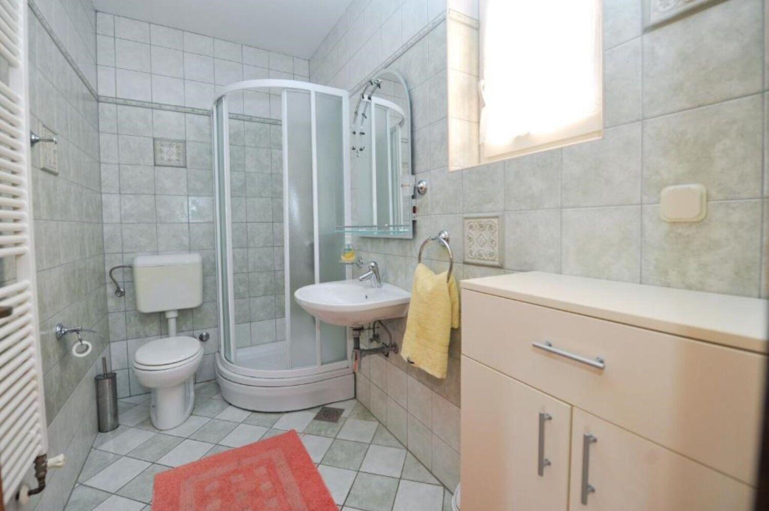 Un bagno con doccia, WC, lavandino e mobiletto.