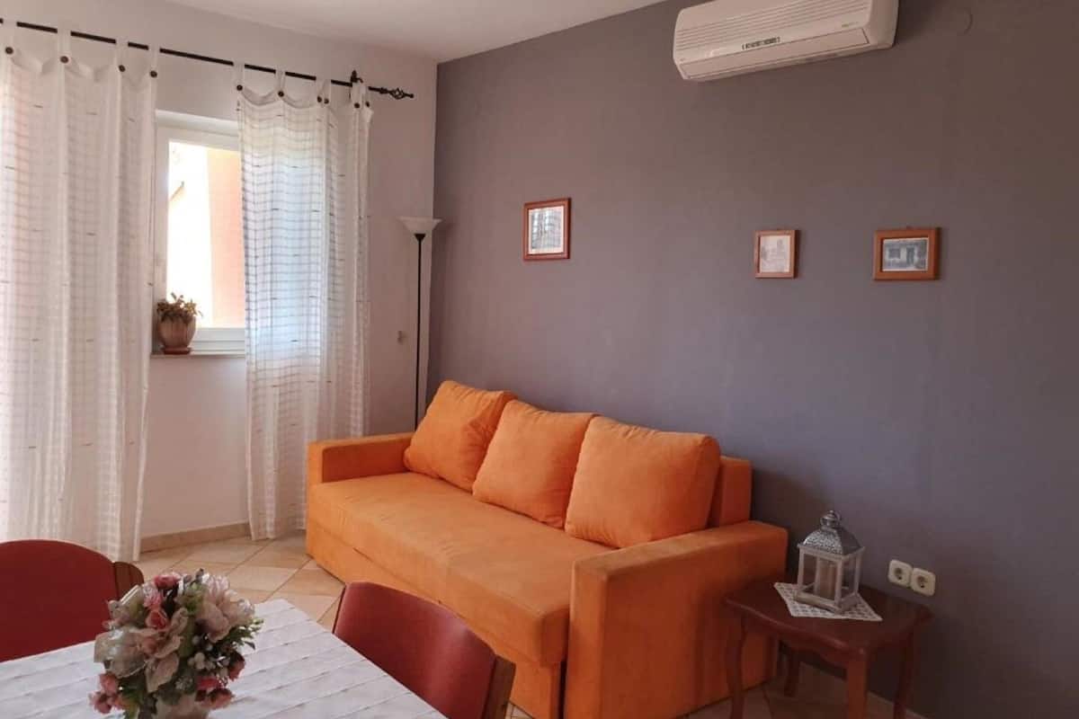 Un salon avec un canapé, une table ornée d’un vase de fleurs et un lampadaire.