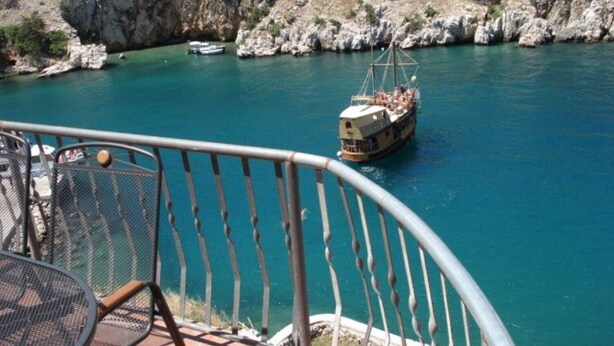 A boat on a turquoise sea with rocky cliffs in the background. - House Bernardica (Vrbnik)