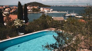A swimming pool with a view of a coastal town and a distant mountain range. - Apartments Novis (Kali)