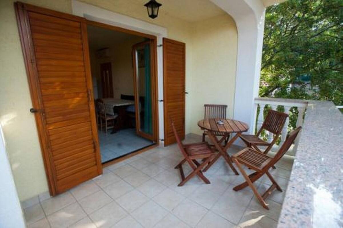 Un balcón con muebles de madera, incluyendo una mesa y sillas, y vistas al exterior.