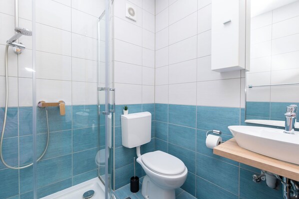 Un baño con cabina de ducha de vidrio, un inodoro y un lavabo con espejo.