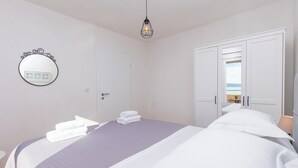 Quarto com cama, guarda-roupa, espelho e luminária suspensa.