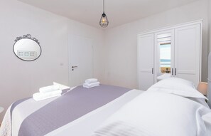 A bedroom with a bed, a wardrobe, a mirror, and a hanging light fixture. - Apartments Marijo (Baska Voda)