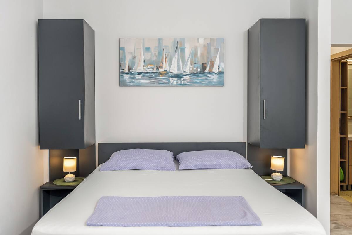 Une chambre à coucher comprenant un lit, deux tables de chevet, un tableau et une armoire.