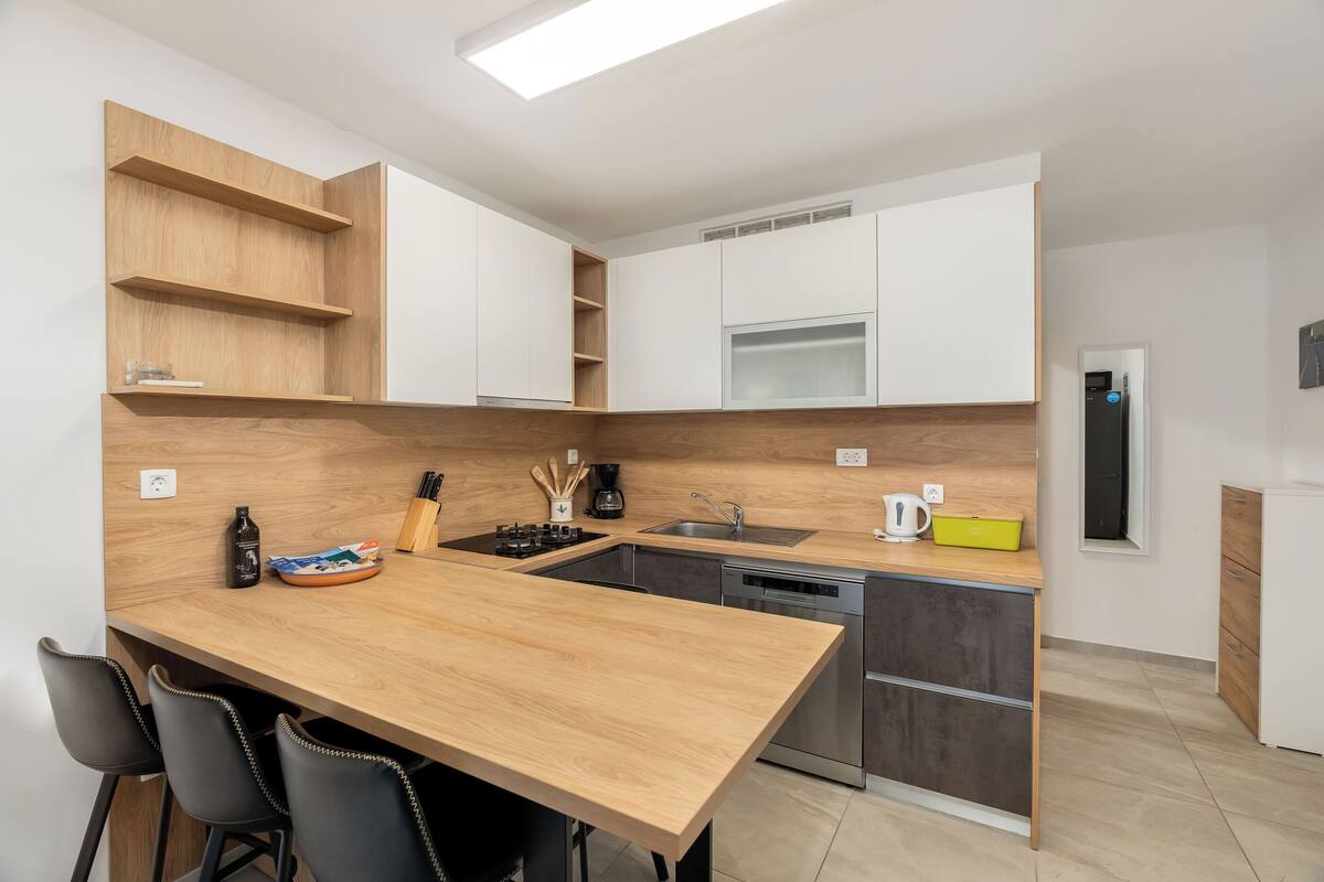 Une cuisine moderne dotée d’un plan de travail en bois, de meubles de rangement intégrés, d’un lave-vaisselle et d’une fenêtre.