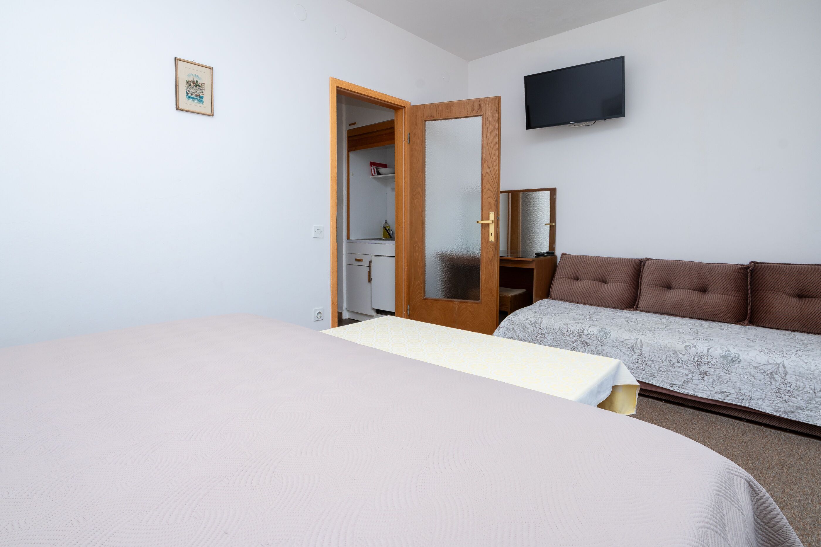 Une chambre à coucher avec un lit, un canapé, une télévision et une armoire.