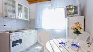 Una cucina con mobili bianchi, un fornello e un tavolo da pranzo con sedie.