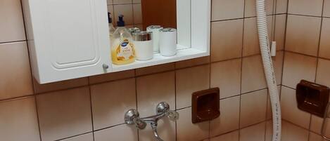 Un baño con lavamanos blanco, inodoro y espejo sobre el lavamanos.