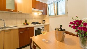 Una cocina con armarios de madera, un lavamanos, una estufa y una mesa de comedor con una copa de vino y un florero.