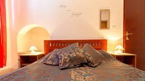 Habitación de hotel con una cama grande, dos mesitas de noche con lámparas, un espejo en la pared y una puerta.