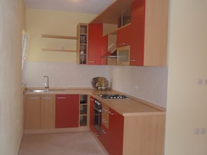 A compact kitchen with wooden cabinets, a sink, and a stove. - Apartment Zana (Sali)