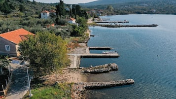 Propiedad frente al lago con muelle, camino de piedra y casas con tejas rojas.