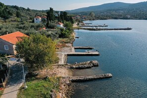 Propiedad frente al lago con muelle, camino de piedra y casas con tejas rojas.