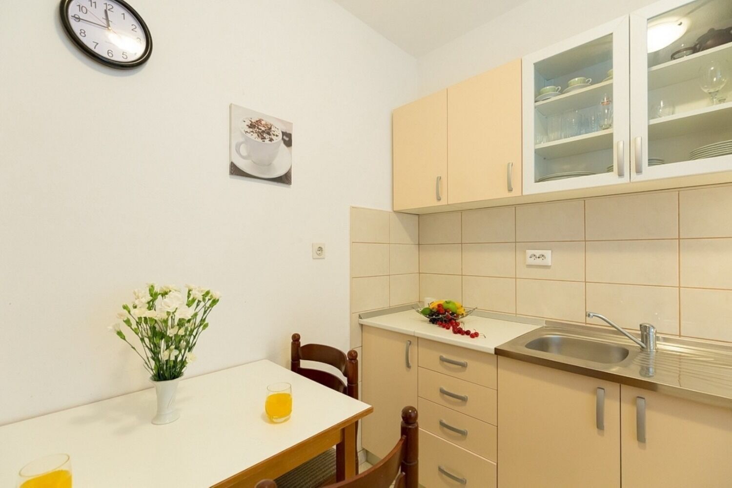 Uma cozinha compacta com pia, armários e um relógio na parede.