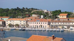 A marina with multiple boats docked, surrounded by buildings with red-tiled roofs. - Apartments Dari (Sali)