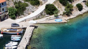 A coastal marina with boats docked, a small swimming pool, and a building with a balcony. - Apartments Dari (Sali)