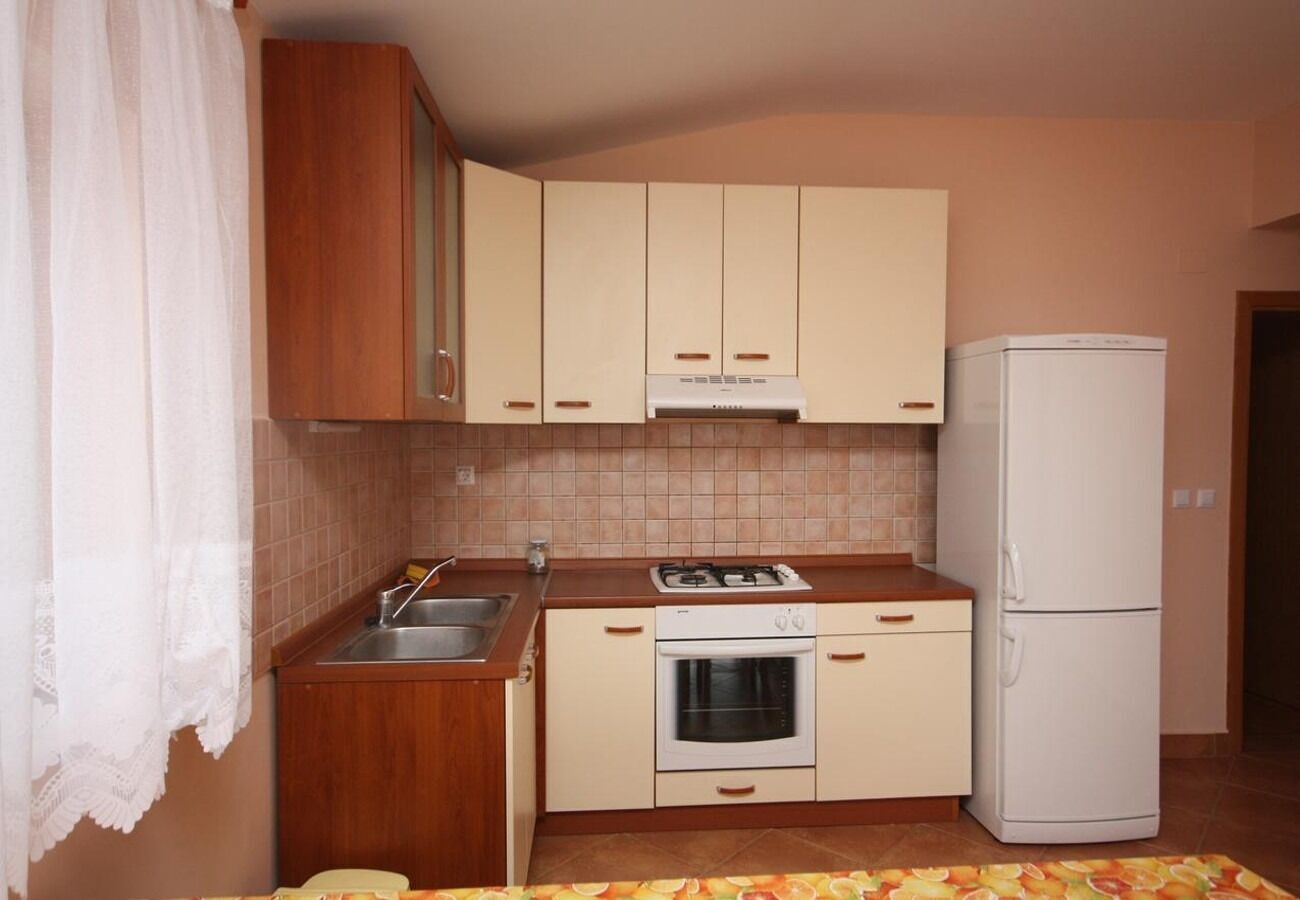 Une cuisine de taille réduite, dotée de meubles en bois, d’une cuisinière à gaz, d’un four, d’un évier et d’un réfrigérateur.