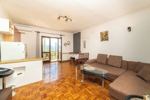 A living room with a sofa, a glass coffee table, and a dining area with a table and chairs. - Apartments Sime (Gradac)