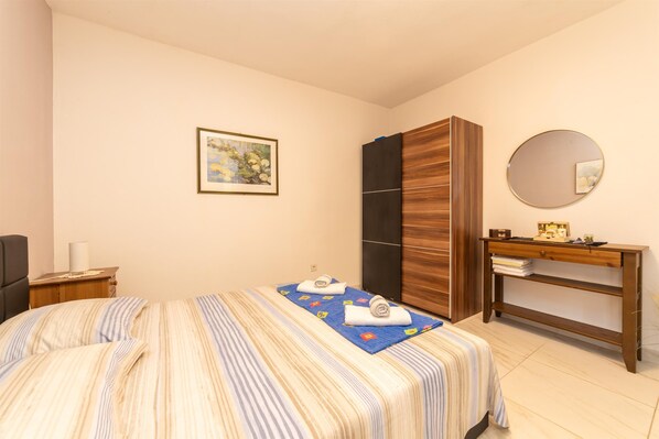Une chambre à coucher comprenant un lit, une armoire, une table de chevet, un miroir et un tableau encadré accroché au mur.