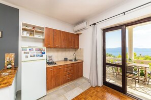 Una cocina con armarios de madera, un refrigerador y una ventana a un balcón con vistas.