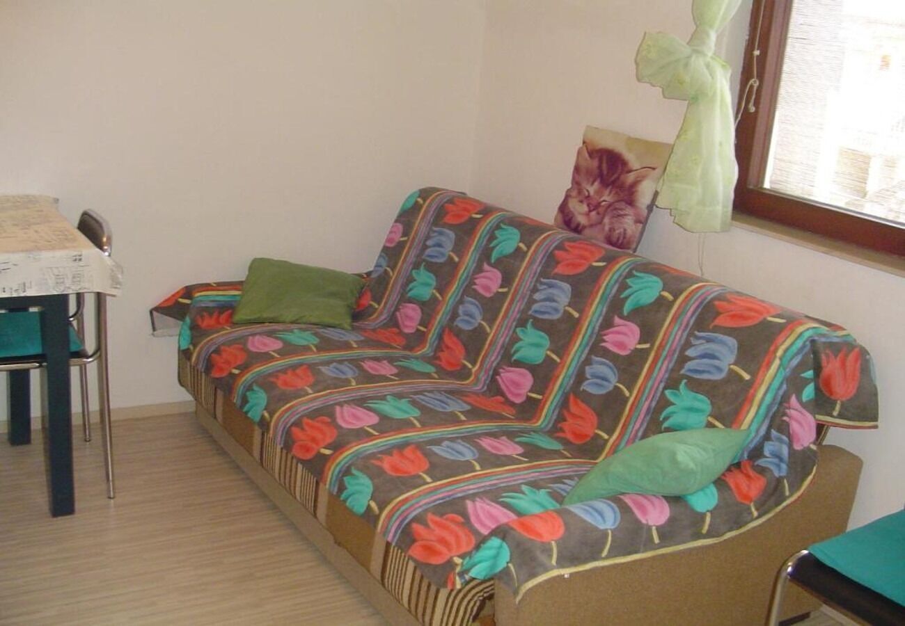 Ein Zimmer mit einer Couch, die mit einer floralen Decke bedeckt ist, einem Sessel und einem Fenster mit Vorhang.