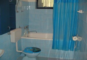 A bathroom with a toilet, sink, bathtub, and blue-tiled walls. - Apartments Nebo (Pakostane)