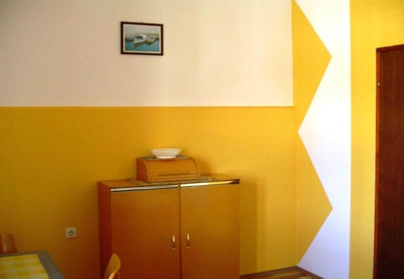 A room with a yellow wall, a wooden cabinet with a bowl on top, and a framed picture on the wall.